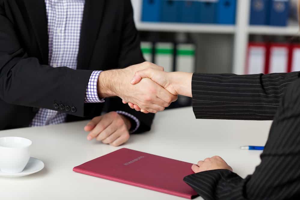 Businessman and businesswoman shaking hands at office desk Businessman and businesswoman shaking hands at office desk